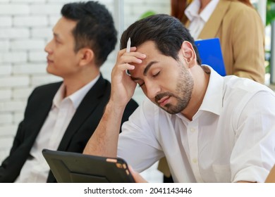 Bored Unmotivated Diverse Caucasian Men Feeling Lack Of Interest During Meeting. Sleepy Worker Feeling Tired At Lecture. Dissatisfied Colleague Looking At Low Energy Man After Meeting Over.