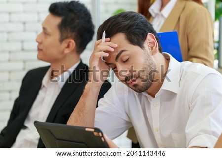 Bored unmotivated diverse Caucasian men feeling lack of interest during meeting. Sleepy worker feeling tired at lecture. Dissatisfied colleague looking at low energy man after meeting over.