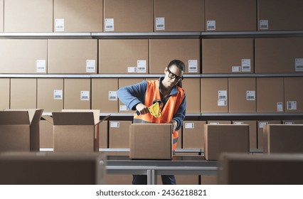 Bored warehouse worker sealing boxes on the conveyor belt with adhesive tape - Powered by Shutterstock