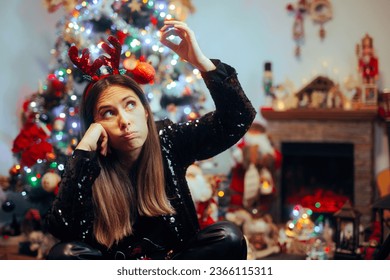 
Bored Woman Holding a Christmas Ornament Waiting for Party Guests. Unhappy girl waiting for Xmas presents opening moment 
 - Powered by Shutterstock