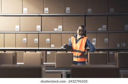 Bored woman working at the warehouse, she is scanning barcodes on boxes with a scanner - Powered by Shutterstock