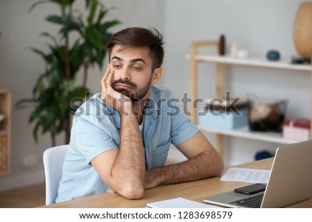 Bored at work concept, tired unmotivated male worker wasting time at workplace distracted from boring job, lazy man disinterested in dull monotonous routine feeling lack of ideas thinking of boredom