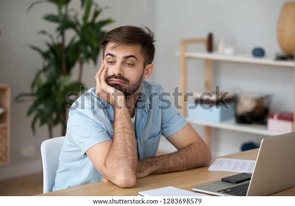 Bored at work concept, tired unmotivated male\
worker wasting time at workplace distracted from boring job, lazy\
man disinterested in dull monotonous routine feeling lack of ideas\
thinking of boredom