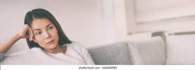 Bored Young Asian Woman Depressed Waiting On Sofa At Home Panoramic Banner.