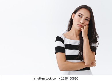 Bored Young Asian Woman Looking Into Distance With Unamused Sad Expression, Lean Face On Fist, Pull Grimace, Annoyed Standing Uninterested Meeting Over White Background, Thinking Pensive