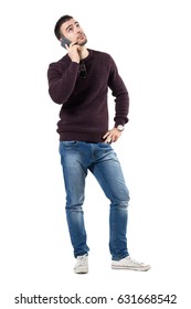 Bored Young Casual Man Listening On The Phone Looking Up. Full Body Length Portrait Isolated Over White Studio Background.