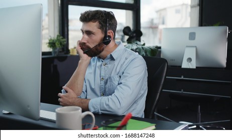 Bored Young Customer Service Executive Talking With Client On Consulting Phone Call Getting Tired Or Unmotivated Working By Computer In The Office.