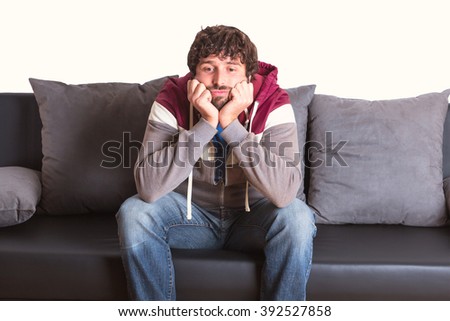 bored young man sitting at home on sofa 