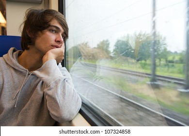 Bored Young Man, Staring Out The Train Window On A Rainy, Grey And Dull Day