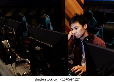 Bored Young Thai Gamer Playing Game On Computer At Internet Cafe.