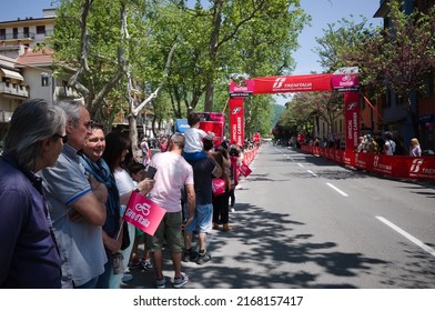 Borgo Val di Taro, Parma, Italy - May, 2022: People with pink flags with logo of Giro d'Italia stand along street waiting for peloton of cyclists at 12th stage of cycling race. Fans waiting for race