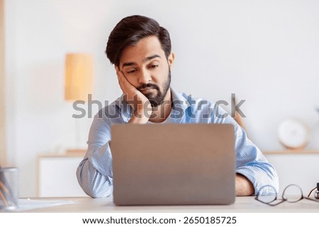 Boring Work. Arab freelancer guy working on laptop with bored face expression