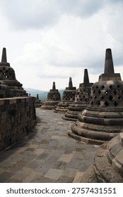 Borobudur, Central Java, Indonesia - July 12, 2024: Majestic stone stupas of the world’s largest Buddhist temple at sunrise. Ancient UNESCO heritage site showcasing intricate reliefs and statues.