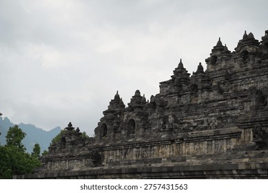 Borobudur, Central Java, Indonesia - July 12, 2024: Majestic stone stupas of the world’s largest Buddhist temple at sunrise. Ancient UNESCO heritage site showcasing intricate reliefs and statues.