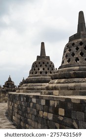 Borobudur, Central Java, Indonesia - July 12, 2024: Majestic stone stupas of the world’s largest Buddhist temple at sunrise. Ancient UNESCO heritage site showcasing intricate reliefs and statues.