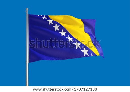 Bosnia Herzegovina national flag waving in the wind on a deep blue sky. High quality fabric. International relations concept.