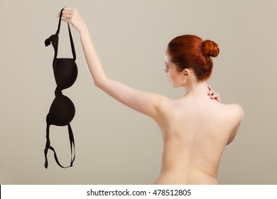 Bosom concept. Slim attractive naked woman holding black plunge bra in hand