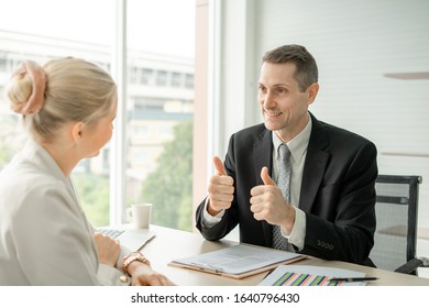 Boss Businessman Doing Thumbs Up Congratulation To Woman Employee At Desk In Office Room