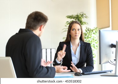 Boss denying something saying no with a finger gesture to an upset employee in her office