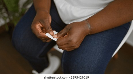 Boss lady, an african american woman, confidently sitting relaxed in waiting room chair, hands holding interview paper - displaying professionalism in indoor meeting background - Shutterstock ID 2395429019