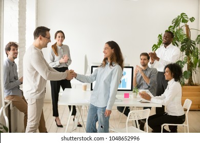 Boss shaking hand of young shy woman congratulating successful employee with promotion, hiring intern, appreciating for good work result, rewarding while business team applauding supporting colleague - Shutterstock ID 1048652996