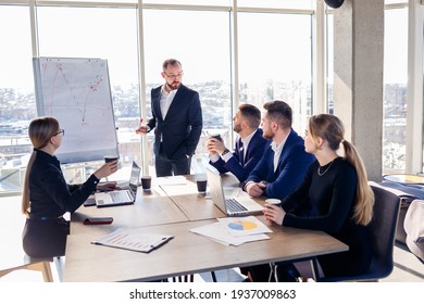 The boss stands near the board with graphs, demonstrates statistics, various personnel attending the training, introduces the new products of the company, reports on the results of work for partners.