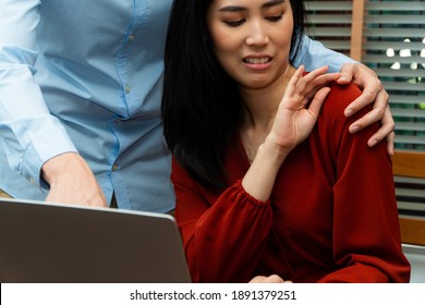 Boss touching shoulder of a young female employee in office at workplace. She is uncomfortable and afraid of sexual inappropriate abuse from a colleague. Concept of sexual harassment in the workplace