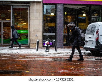 Boston Massachusetts, December 3rd, 2019: A person dressed in black steps along a brick lane during a winter flurry.
