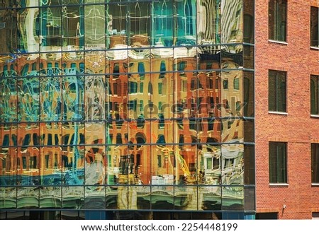 Boston, reflections of old and new buildings in mirrored modern building. Row houses, apartments and buildings mirrored in glass building. Color photo.