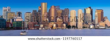 Boston skyline panorama at dawn with sailboat in foreground and blue sky 