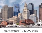 Boston skyline with tall modern buildings, Custom House Tower (a Boston landmark), and waterfront with boats and large yacht anchored in the harbor.