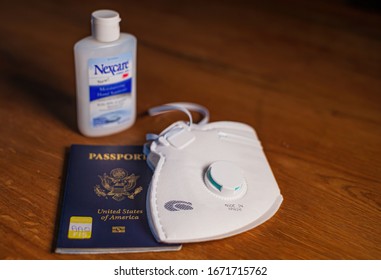 Boston, USA - 13 March 2020: Close Up Of Mask, US Passport And Desinfactant On The Table Ready For Travel In Times Of Coronavirus Pandamic.