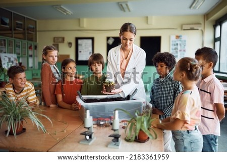 Botany professor teaching school kids to plat flower during a class at school.