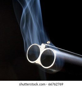 Both barrels of a double barreled shotgun belching smoke after shooting