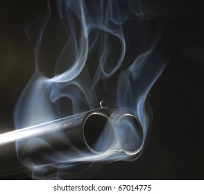 both barrels of a shotgun that are pouring out smoke