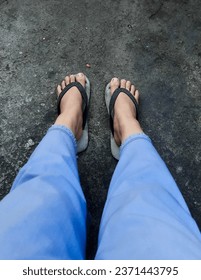 both feet wearing sandals wearing blue pants on the street photo from above