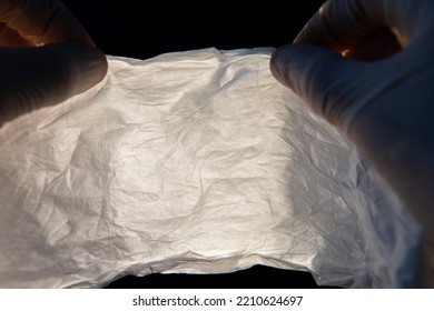 Both Hands In Gloves Holding Wrinkled Nanofiber Material. Nanofibers In Backlight.