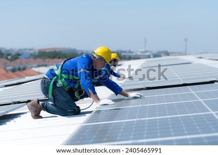 Both of technicians is installing solar panels on the roof of the warehouse to change solar energy into electrical energy for use in factories.