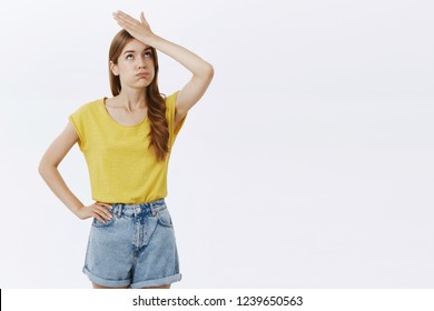 Bothered and pressured good-looking female feeling troubled and loaded with work making facepalm gesture exhaling and pouting lifting eyelids up from irritation and exhaust over gray background
