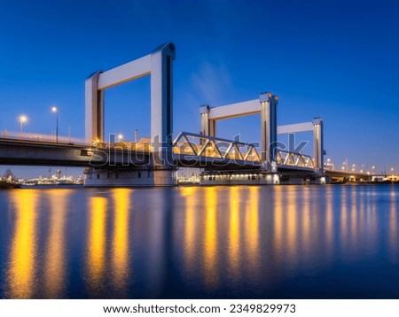 Botlek bridge, Rotterdam, Netherlands. View of the bridge at night.  Road for cars and railroad transport. Architectural landscape. Reflections on the surface of the water.