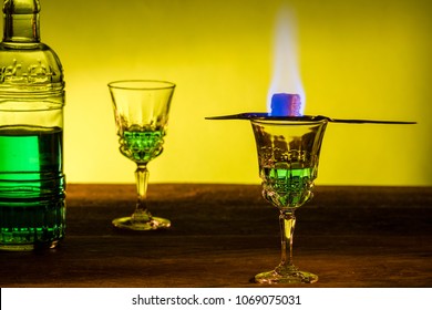 Bottle Of Absinthe And Glasses With Burning Cube Brown Sugar.