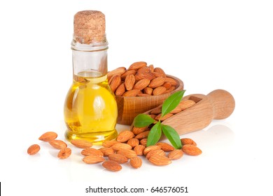 Bottle of almond oil and almonds with leaf in a wooden bowl and scoop isolated on white background