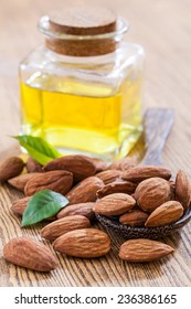 Bottle almond oil and almond on wood background