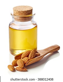 Bottle of almond oil and wooden scoop of almonds isolated on white background