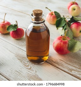 a bottle with apple cider vinegar and apples on a light table