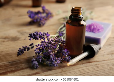 Flasche mit Aromaöl und Lavendelblumen auf Holzhintergrund