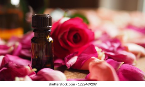 Bottle of aroma oil with red rose and roses petals on wooden surface selected focus - Powered by Shutterstock