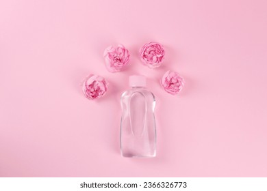 Bottle with baby oil and beautiful flowers on pink background, flat lay. Space for text - Shutterstock ID 2366326773