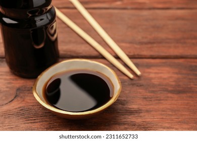 Bottle, bowl with soy sauce and chopsticks on wooden table, closeup. Space for text - Powered by Shutterstock