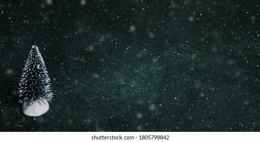 Bottle Brush Christmas Tree On Dark Green Background With Snow For Holiday Copy Space.